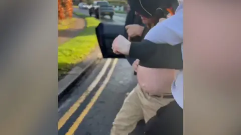 A man is led to the side of the road.