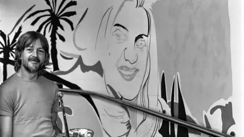 Ken White stands next to a mural of Diana Dors he produced in the mid-1980s for the Brunel Shopping Centre in Swindon.