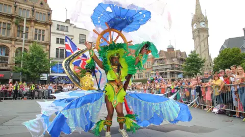 Leicester Caribbean Carnival Woman dressed in a colourful costume as part of the Leicester Caribbean Carnival troops in the parade near the clocktower in the city centre