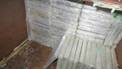 National Crime Agency Picture of wrapped slabs containing cannabis which have been pilled up and  hidden inside a piece of machinery.