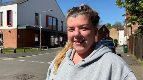 Woman stands on street.