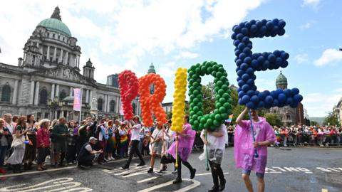 People taking part in the Belfast Pride Parade 2023 carrying balloons that spell out PRIDE
