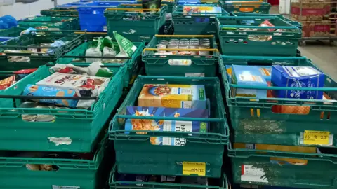 Coventry Foodbank Crates of supermarket items, including cereal and tins of soup.