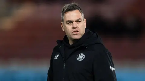 Johann van Graan walking on the pitch with his arms in his pockets during a pre-match warm-up