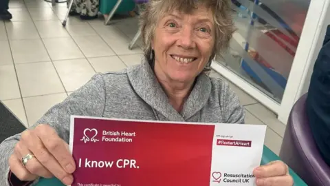 Andrea Quigley holding a certificate saying 'I know CPR' 