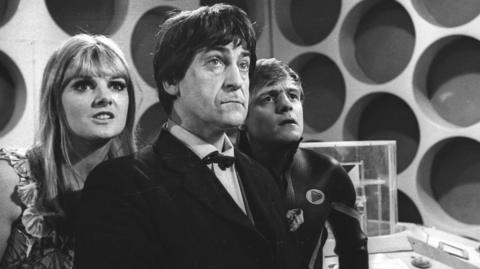 Patrick Troughton as Doctor Who stands with companions in the Tardis control room