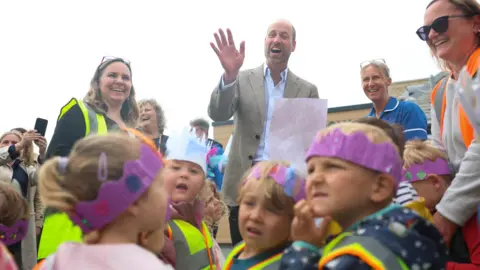 PA Media Prince William is pictured smiling and waving as he met local nursery students and staff during his visit to the Isles of Scilly
