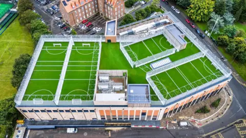 Spelthorne Borough Council An aerial image of four green multi-sport rooftop pitches.