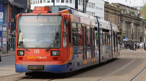 A red and blue tram drives through Sheffield city centre.