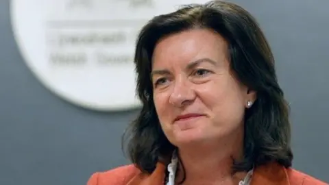 BBC Health Minister Eluned Morgan wearing orange suit.