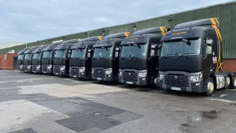 BJS Haulage A line of nine black haulage trucks.