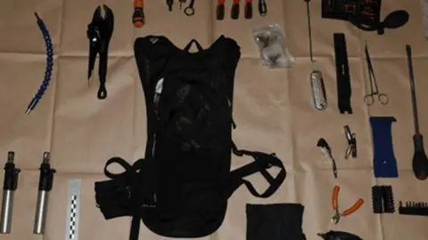 GMP Tools, including screwdrivers, pliers, a rucksack and bolt cutters laid out on brown paper