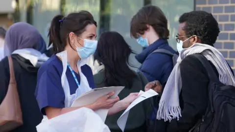 PA Media A nurse hands out forms to a queue lining up for a meningitis jab.