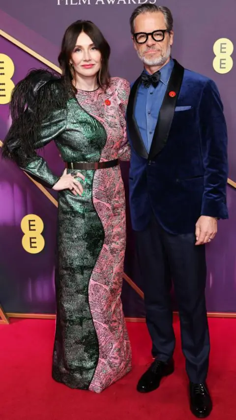 Getty Images Carice van Houten and Guy Pearce; she is in a green and pink dress and he is in a blue, velvet suit