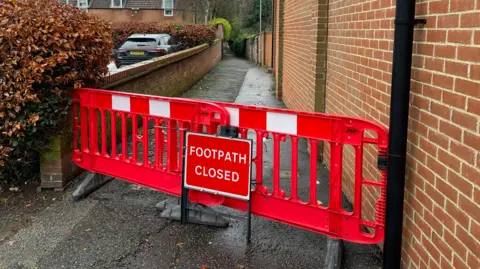 Edd Smith/BBC A red blockade and a sign saying footpath closed at the entrance to an alleyway 