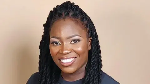 Joshuanette Francis poses for a photo. She is wearing a T-shirt which reads "Be a Good Human"