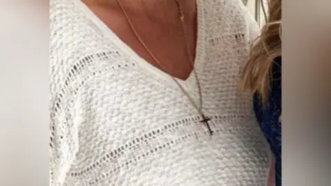 Essex Police A woman wearing a gold cross around her neck. Her face has been cut out of the photo and she is wearing a white blouse.