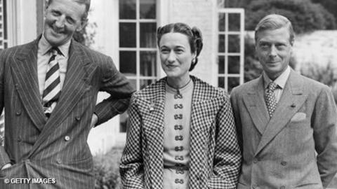 A black and white image of Major Edward Dudley Metcalfe and The Duchess and Duke of Windsor, outside Metcalfe's country house.  All are smiling (the Duke slightly less so) and looking over the left shoulder of the camera.
