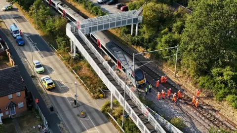 PA Media A drone image showing police and railway workers assessing the train and railway tracks.