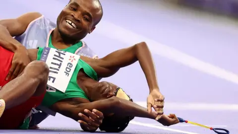 Franck Fife / AFP Pelari Namibia Lahja Ishitile pingsan di lintasan balap bersama pemandunya Sem Shimanda setelah memenangkan Final 400m T11 Putri di Paralimpiade Paris - Sabtu 31 Agustus 2024