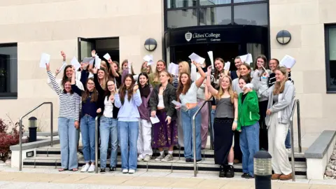 Ladies' College Students on the steps of Ladies' College holding their exam results in the air