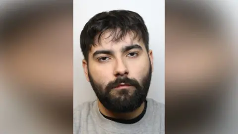 Mugshot of Kyum Raham, who has a beard and wears a grey t-shirt