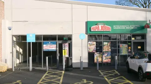 A row of two shops in Bradford. One is closed and has an under offer sign on it the neighbouring property is a pizza takeaway