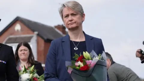 PA Media Yvette Cooper walks holding a bouquet of flowers