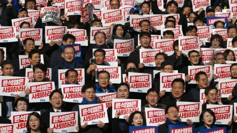 AFP via Getty Images Lawmakers and South Korea's main opposition Democratic Party members hold placards reading "Yoon Suk Yeol should resign!" during a rally against President Yoon Suk Yeol at the National Assembly in Seoul on December 4, 2024, 