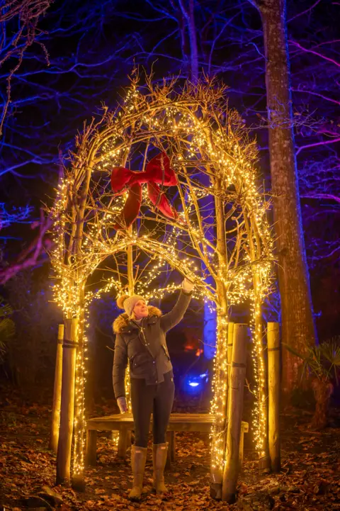 Phil Wilkinson A woman stands under an archway of lights with a bow on the front of it