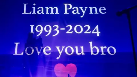 Getty Images A written tribute to Liam Payne appears onscreen during Zayn's performance at O2 Academy Leeds on November 23, 2024 in Leeds, England. 