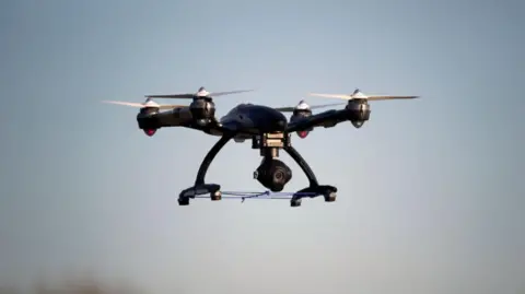 A black drone with a camera flying in the sky 