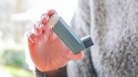 Person holding a blue asthma inhaler.