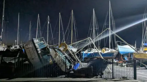 Barry Corr A row of boats in a harbour lie on their side in the dark