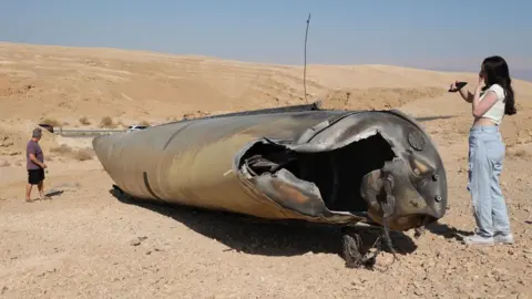 EPA employees inspect the wreckage of an Iranian ballistic missile outside the city of Arad in southern Israel