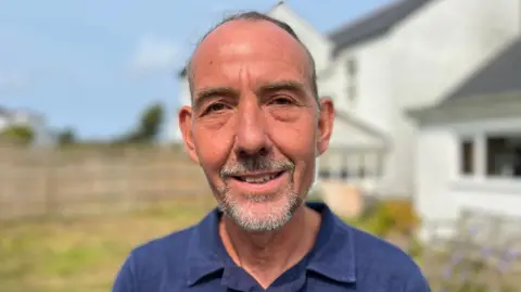 BBC Deputy Steve Falla in a blue shirt, smiling at the camera