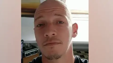 A picture of Daniel Backhouse-Dyson who died after falling of his motorcycle. He is wearing a dark t-shirt and has a short goatee beard and a shaved head