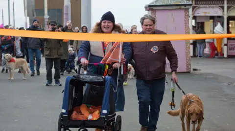 Sarah Summerton Gemma Fairhurst smiles as Mark Fielding walks his guide dog Ian to the finishing line of the charity walk on Blackpool Promenade.