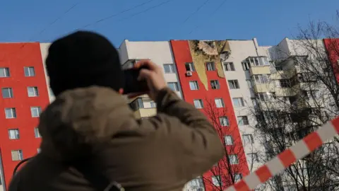 A man takes a photo of a building in Moscow which was hit by a drone attack in March 2025. 