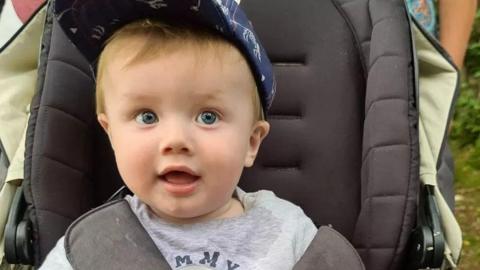 Oliver Steeper, who died aged nine months, in his pram wearing a blue cap and grey shirt