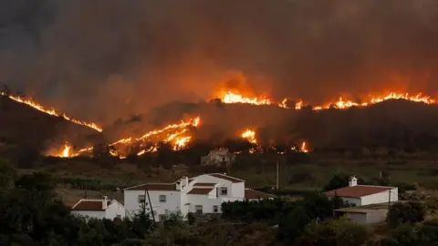 Getty Images Flames tear through the hills around houses.
