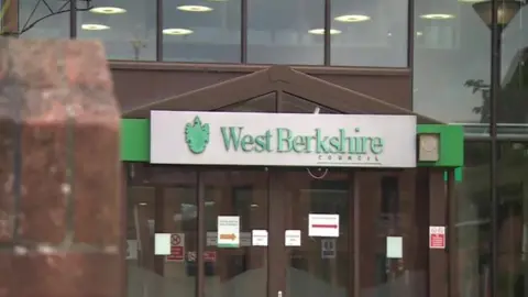 BBC The exterior of West Berkshire Council Offices, including a large glass facade and a silver sign with the council's name in green letters.