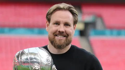 Gateshead boss Rob Elliot at Wembley Stadium with the FA Trophy