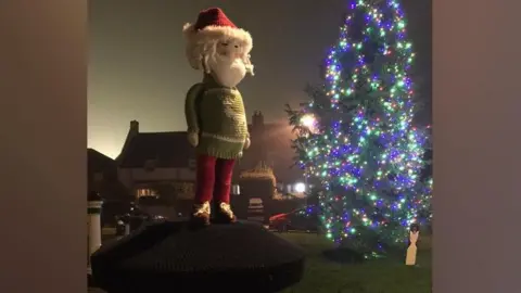 Ashley Briggs Knitted Santa topper overlooking the Christmas Tree 