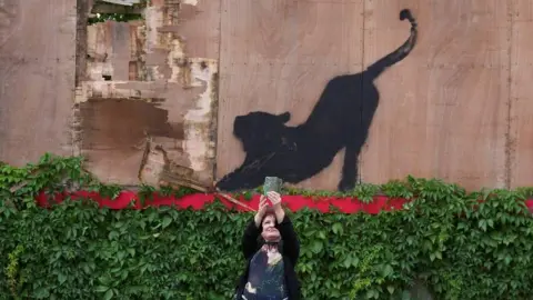 Reuters A woman takes a selfie next to the painting. 