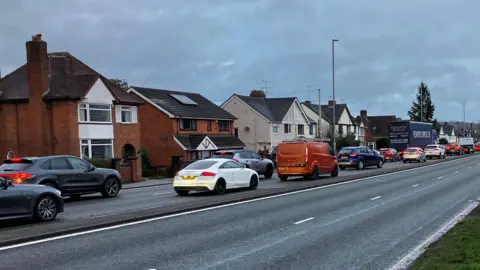 A series of cars building up along a main road.