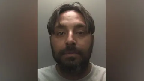 Leicestershire Police Amritpal Singh, in a grey top standing against a grey wall