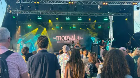 A crowd looking at a stage, with 'Morvala' in lights