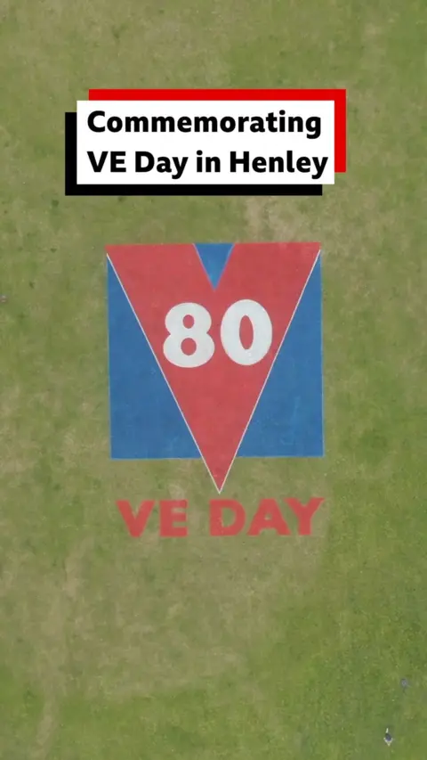 Red and Blue VE Day 80 logo on grass
