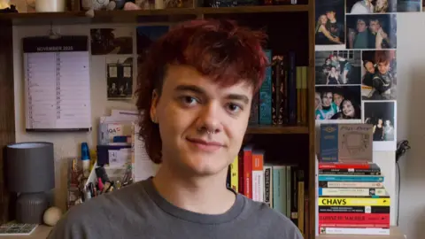 James Green A man with brown hair and a brown jumper